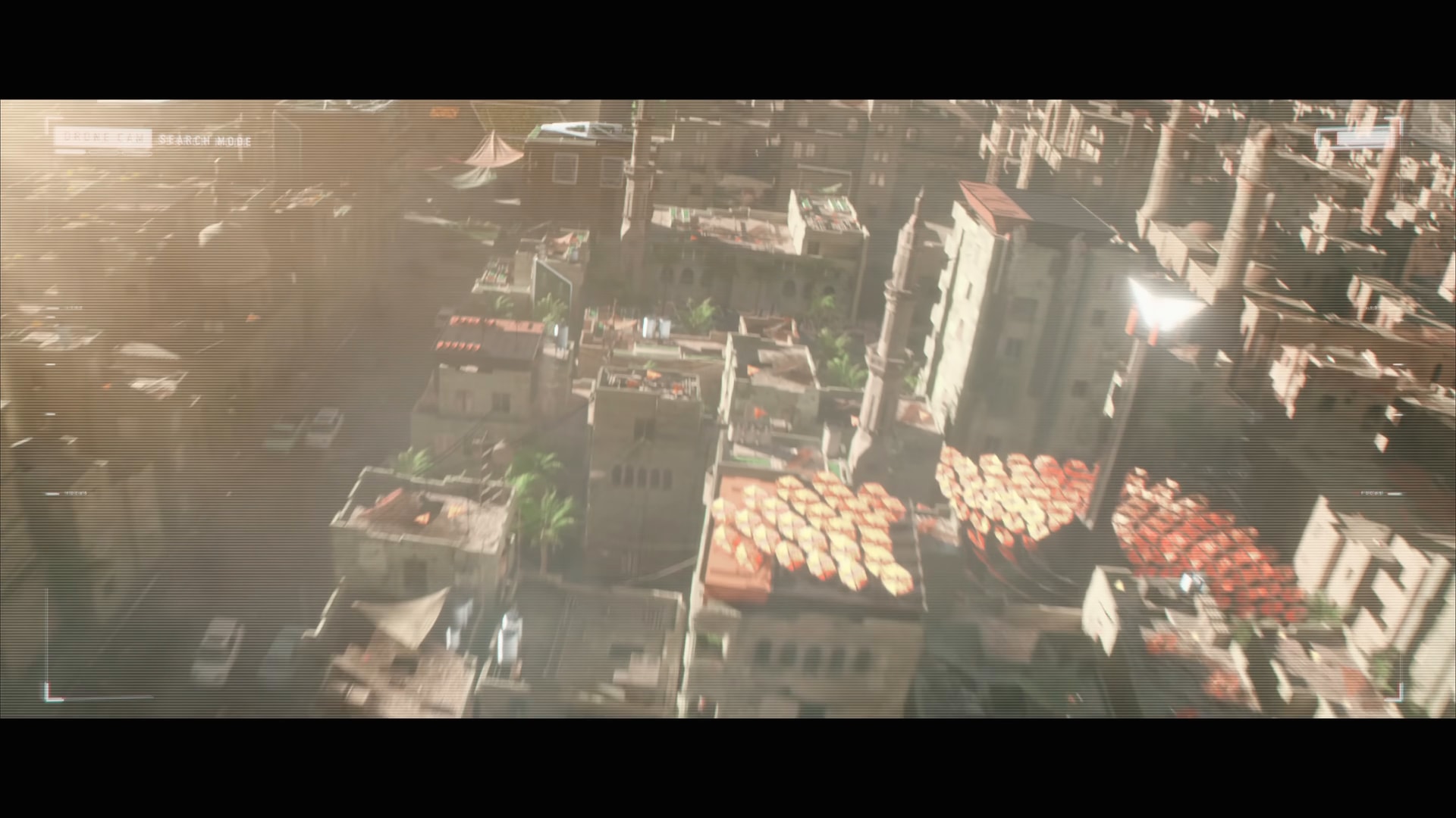A rooftop solar array of orange dishes beside a tall mast, minarets and planted terraces around it, seen from the drone